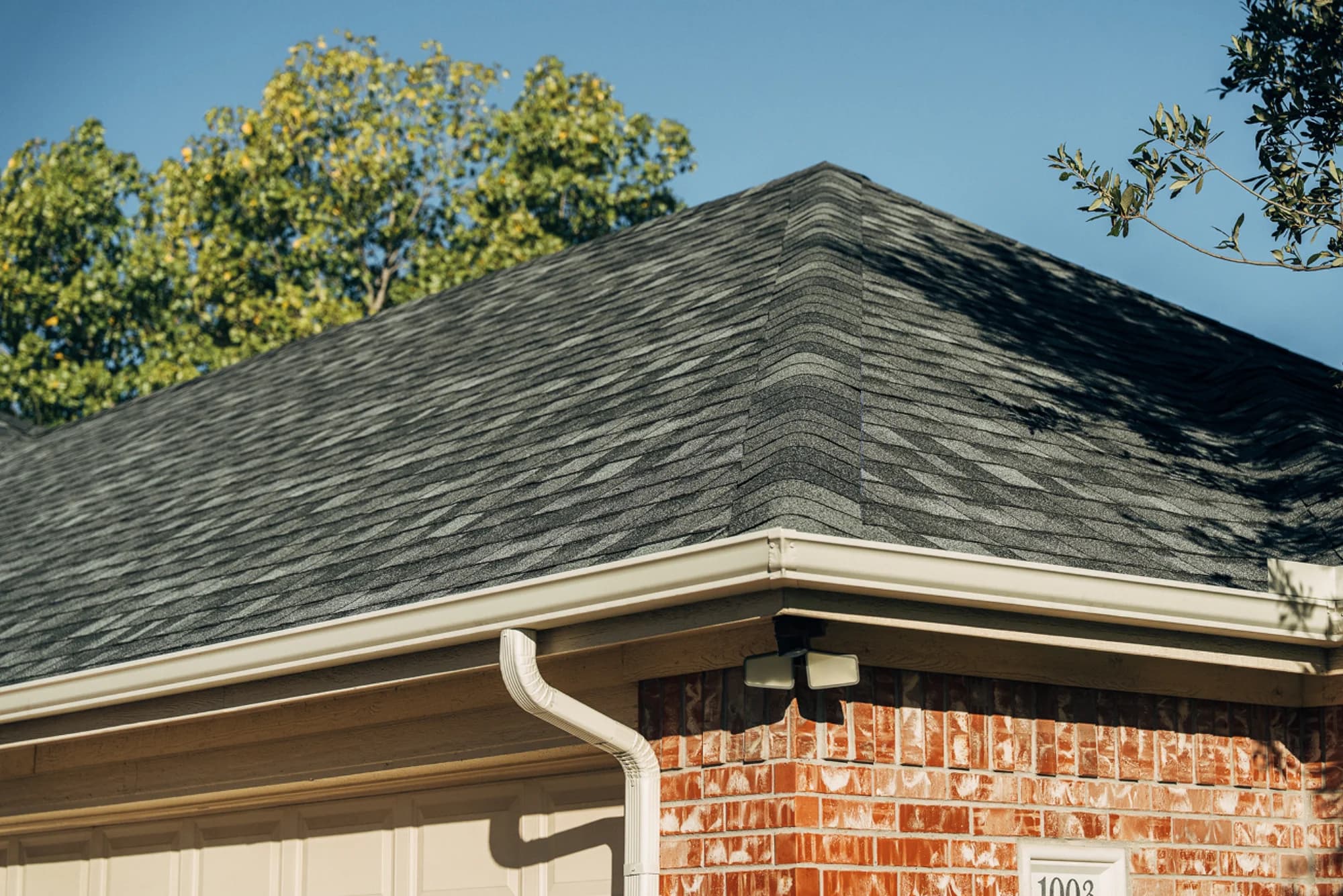 Completed dark asphalt shingle roof on a brick home