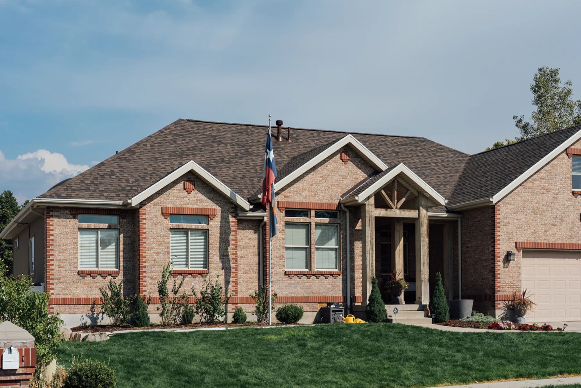 A completed asphalt shingle roof on a brick home