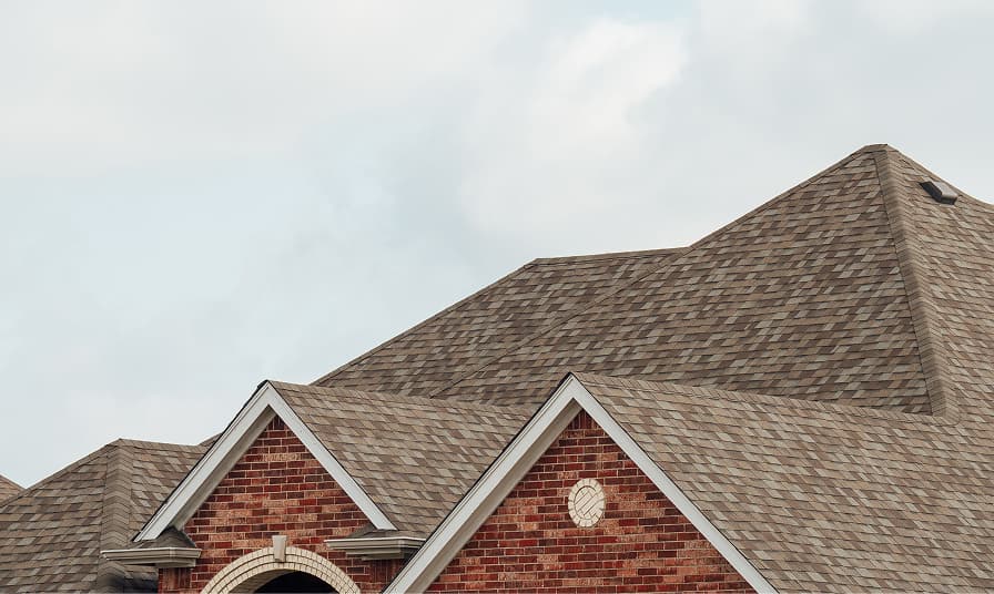 A completed asphalt shingle roof on a brick home